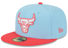 Load image into Gallery viewer, A fitted baseball cap with a two-tone design, predominantly light blue on top and red on the brim, featuring an embroidered bull's face logo in pink on the front.