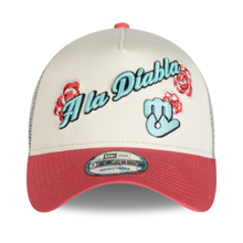 Load image into Gallery viewer, A New Era trucker hat with an off-white front panel and a red brim, featuring 'A La Diablita' embroidered in light blue script with red roses and a light blue devil graphic on the front. The back is mesh, and a New Era 9FORTY sticker is visible on the brim.