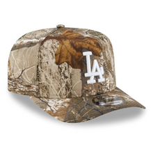 Load image into Gallery viewer, A baseball cap featuring a brown and beige woodland camouflage pattern with a white embroidered 'LA' logo on the front.