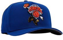 Load image into Gallery viewer, A royal blue New York Knicks baseball cap with a detailed embroidered front logo featuring basketballs, a hockey player, and the team name.
