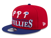 Load image into Gallery viewer, Red and blue Philadelphia Phillies cap on a red background and with a blue visor.